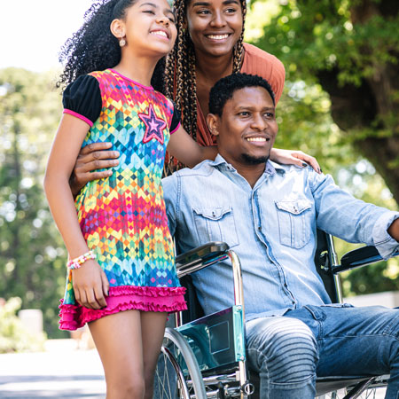 African American Man in Wheelchair with Two Daughters Standing Near Him