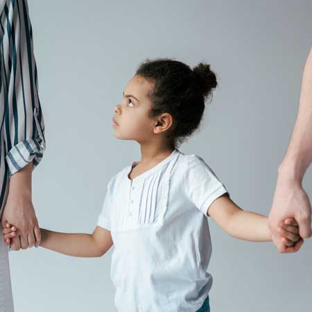 Young African American girl holding parent's hands